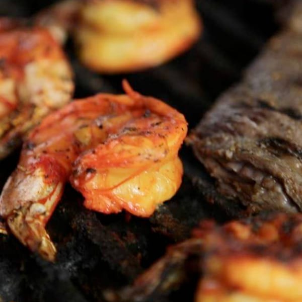 Shrimp and fish grilling on a dark, textured surface at Tortuga's Mexican Village.